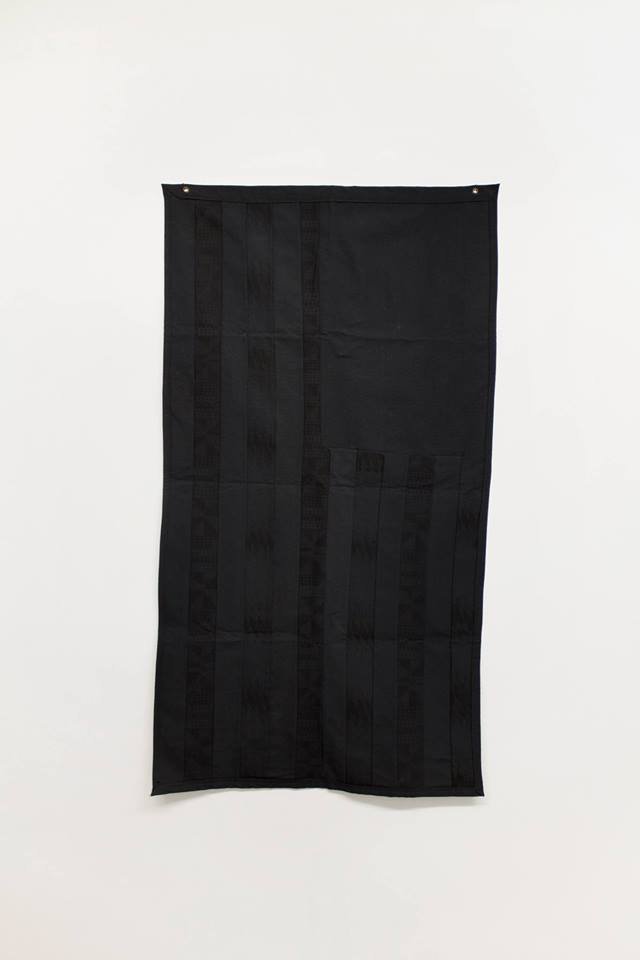 A all black American flag hangs in an empty white space