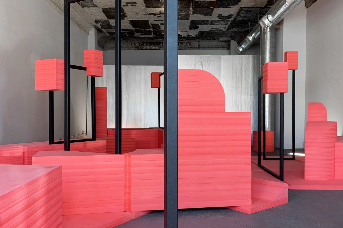 Photograph depicting various geometric red shapes connected by straight black bars throughout a room