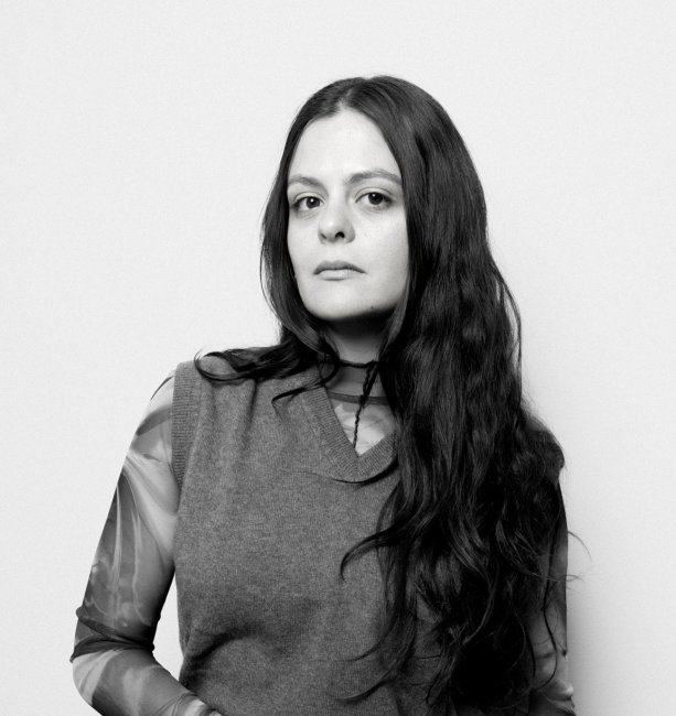 Grayscale photograph of Inés Arango-Guingue wearing a sweater vest and looking at the camera.